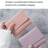 A close-up of a pink leather fashion purse being held by a hand against a gray background.