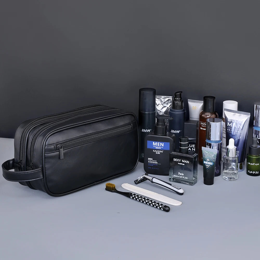 A black premium PU leather toiletry bag is shown with various grooming products and tools on a gray surface.
