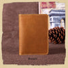 A brown genuine leather passport wallet with card holders resting on a dark brown textured surface.