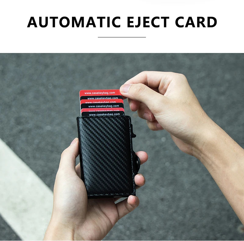 A hand holds a black carbon fiber RFID pop-up card holder displaying several cards.