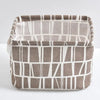A rectangular storage basket made of brown and white striped fabric for desk organization.