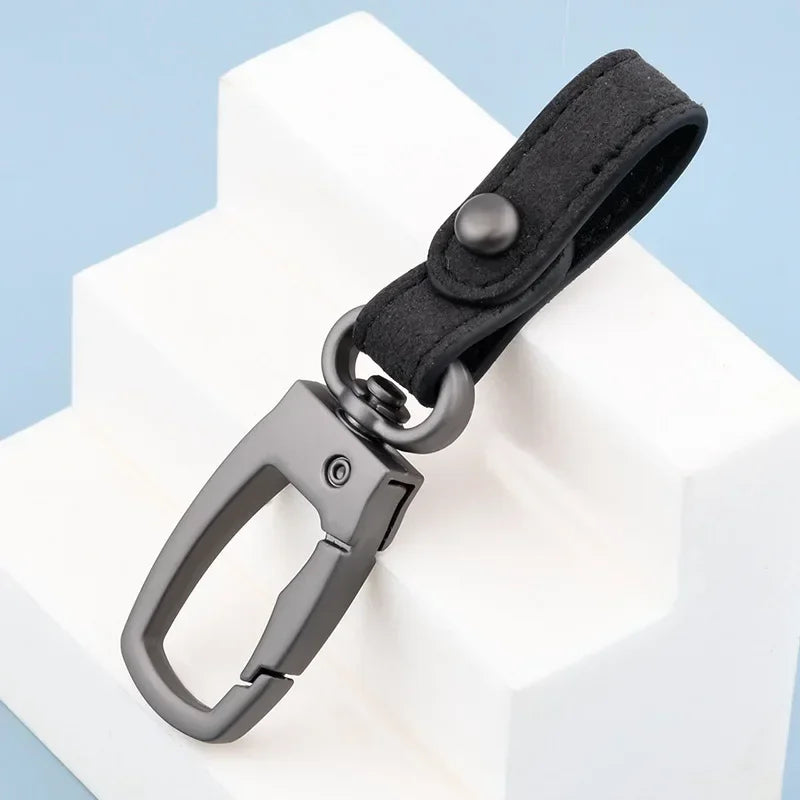 A black genuine leather keyring keychain attached to a white block.