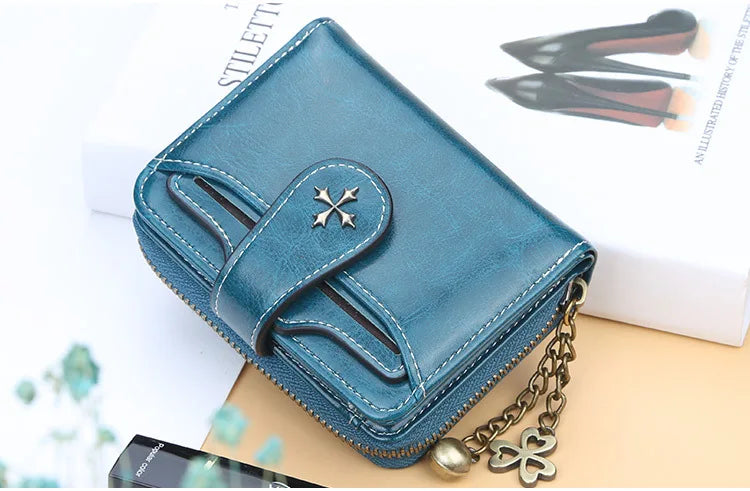 A teal PU leather compact wallet with a zipper and gold chain resting on a light background.
