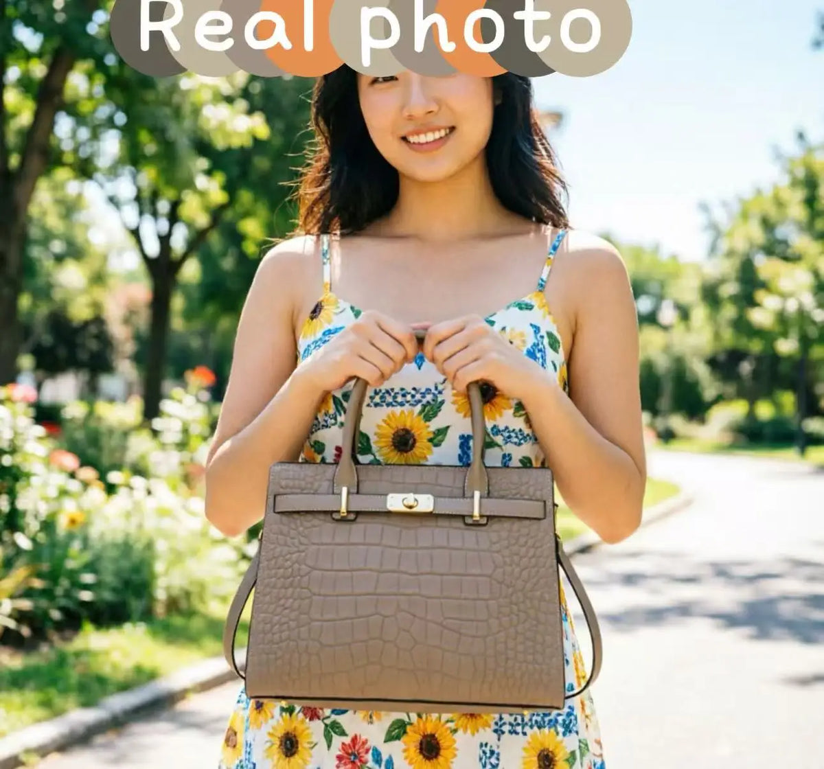 A woman holds a brown genuine leather shoulder bag outdoors in a park setting.