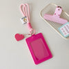 A pink PU credit card and ID holder keychain with a clear plastic cover and a pink strap is displayed next to a pink plastic 