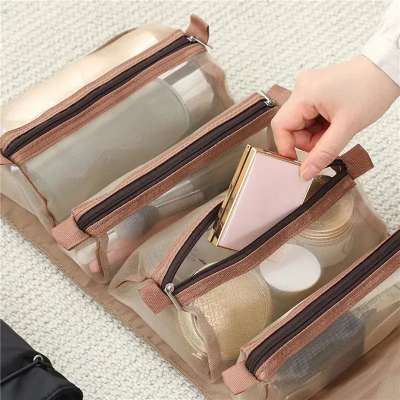 A hand is opening a clear portable makeup bag with a brown strap, revealing cosmetic containers inside.