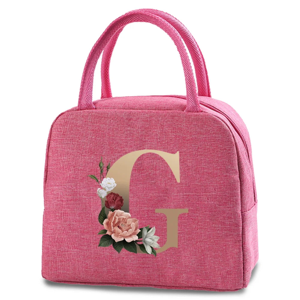 A pink insulated canvas lunch bag featuring a large gold letter G print.