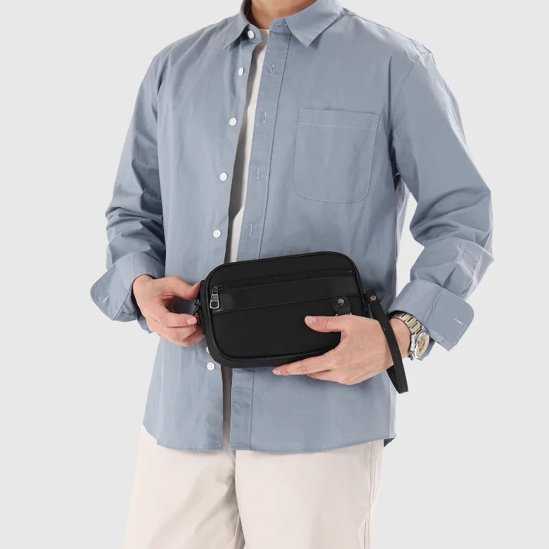 Una mujer vistiendo una camisa azul claro sostiene un bolso cruz de cuero sintético negro.
