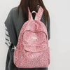 A pink leopard print laptop backpack with padded straps carried by a person.
