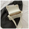 A white vintage curved flap shoulder bag with light tan lining rests on a dark gray fabric.