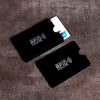 A black RFID protection card sleeve with a white card inside, resting on a brown fabric surface.