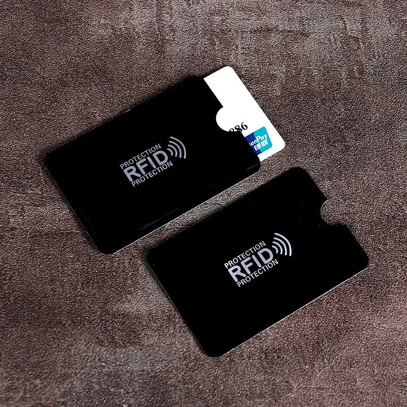 A black RFID protection card sleeve with a white card inside, resting on a brown fabric surface.