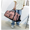 A person is holding a pink tactical backpack with black accents against a white wall.