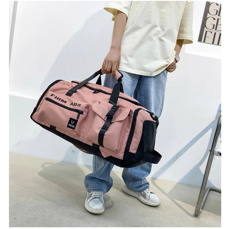 A person is holding a pink tactical backpack with black accents against a white wall.