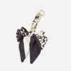 A black and white patterned adjustable bag strap with a gold-toned clasp.