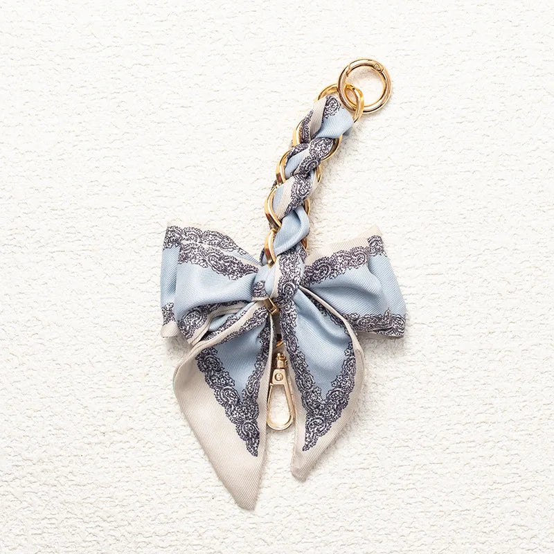A light blue and gray patterned fabric adjustable bag strap with a gold-toned clasp.