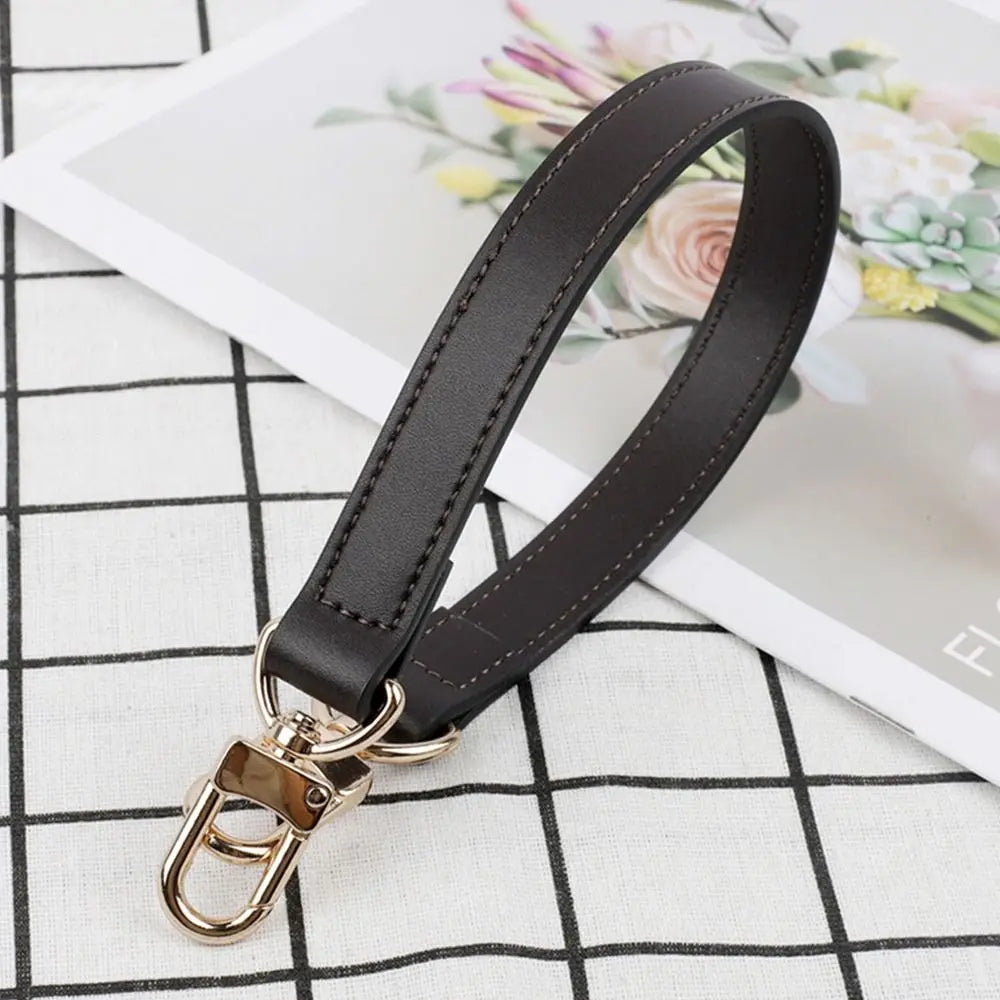A black genuine leather replacement shoulder strap with a gold-toned metal clasp is displayed on a white background.