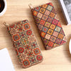 A patterned bohemian wood-grain leather wallet with multiple card slots resting on a light wooden surface.