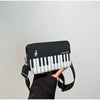 A black crossbody bag featuring a white piano print embroidery on the front, held by a person.