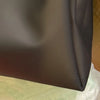 Un sac fourre-tout en gelée transparente gris foncé, vu de côté.