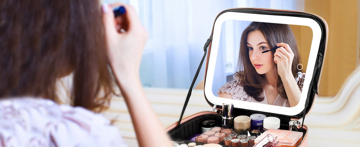 A woman applies makeup using an LED lighted train case with adjustable dividers.