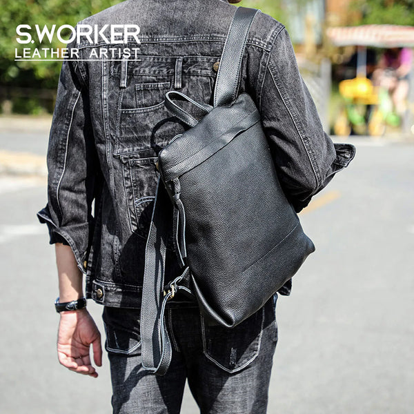 A person wearing a dark denim jacket and jeans carrying a black full-grain leather backpack.