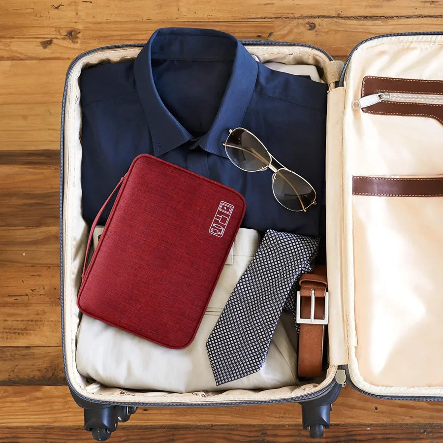 A navy blue shirt is displayed inside a light-colored organizer pouch with a maroon leather storage pouch and a brown leather