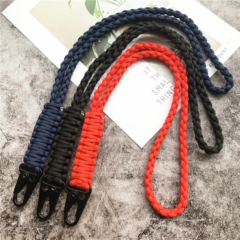 A collection of hand-woven nylon lanyards in blue, black, and orange with metal hooks displayed on a light surface.