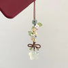 Un pendentif délicat avec un cluster de petites fleurs et un charm en forme d'étoile clair et translucide sur un fil brun.