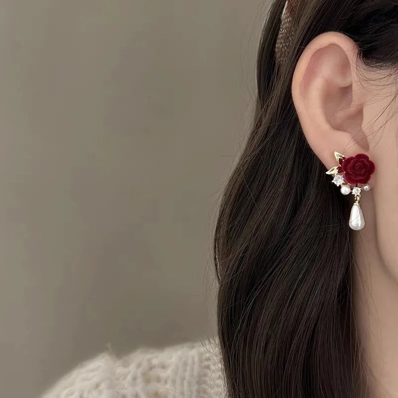 A close-up of a woman's ear featuring vintage velvet rose pearl stud earrings.