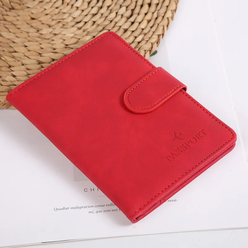 Portefeuille passeport en cuir rouge posé sur une surface blanche à côté d'un panier tissé.