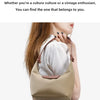 A woman is holding a beige nylon dumpling crossbody shoulder bag with a white ribbed sweater and blue jeans.
