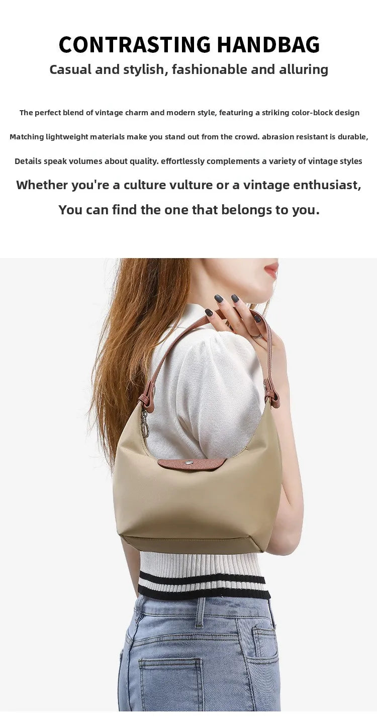 A woman is holding a beige nylon dumpling crossbody shoulder bag with a white ribbed sweater and blue jeans.