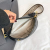 A black PU leather crossbody bag with a patterned strap is shown open on a light surface.