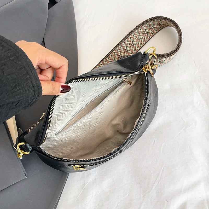A black PU leather crossbody bag with a patterned strap is shown open on a light surface.