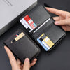 A black slim PU leather credit card wallet is shown open, displaying various cards and held by a hand against a gray box.