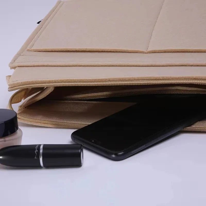 A stack of tan felt purse organizers with a black smartphone and a black cylindrical item on a white surface.