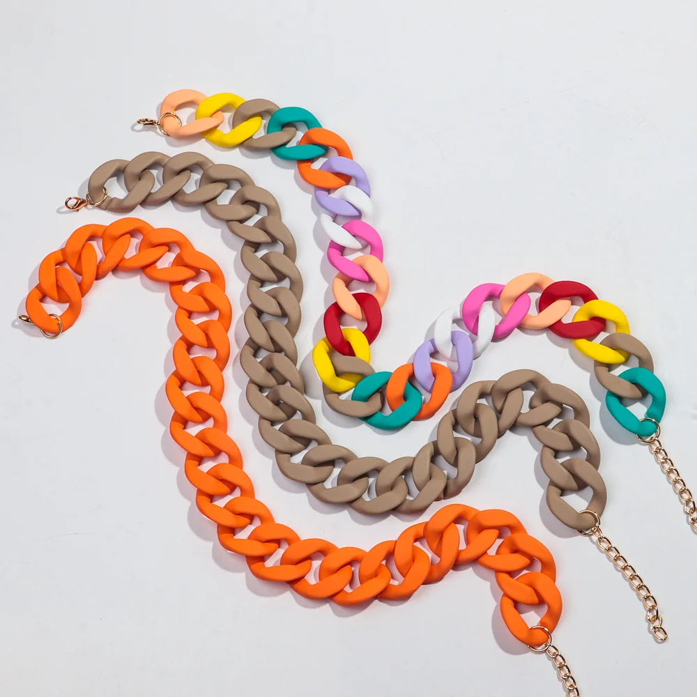 A display of multiple colorful matte acrylic chain necklaces arranged in a serpentine pattern.