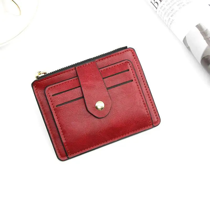 A maroon leather card holder wallet with a flap closure and coin pocket shown on a white background.