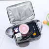 A silver zippered insulated lunch bag is open, revealing a dark pouch containing various cosmetic and personal items.