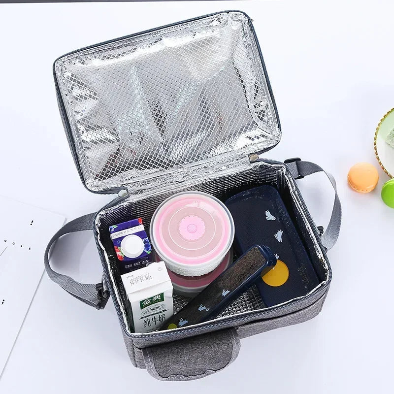 A silver zippered insulated lunch bag is open, revealing a dark pouch containing various cosmetic and personal items.