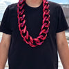 A man wearing a black t-shirt and a chunky red acrylic Cuban link necklace.