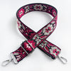 A black and pink floral patterned fabric strap for a crossbody bag, featuring a silver buckle.