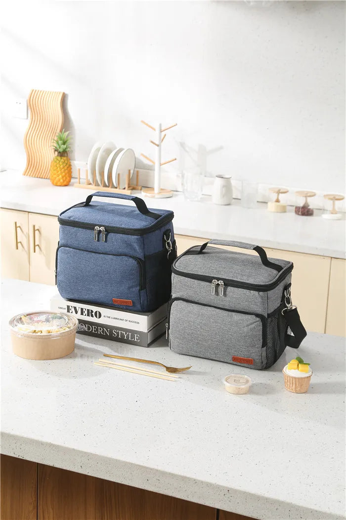 A blue insulated thermal lunch bag sits on a white countertop next to various kitchen items and food.