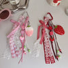 A collection of pink and red strawberry bag charm keychains with lace and ribbon details.