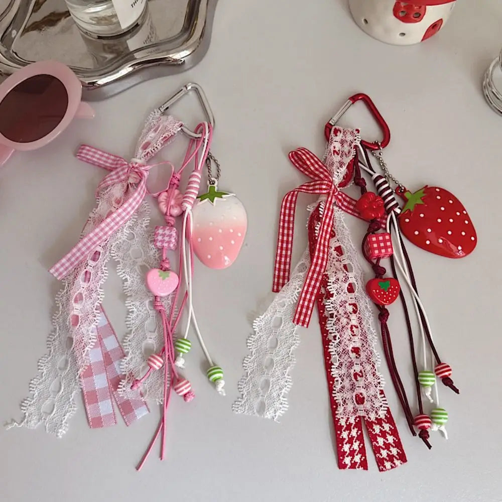 A collection of pink and red strawberry bag charm keychains with lace and ribbon details.