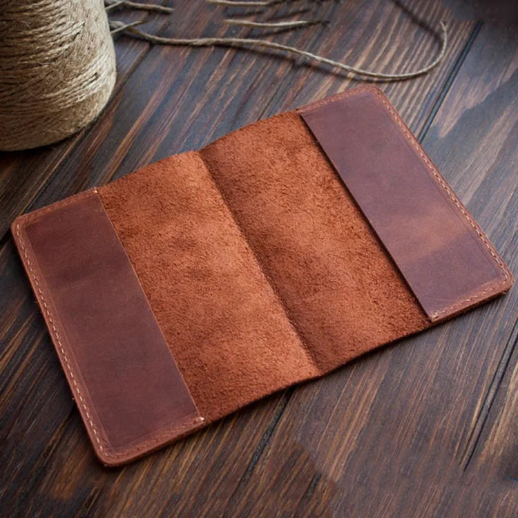 A brown genuine leather passport holder with card slots resting on a dark wooden surface.
