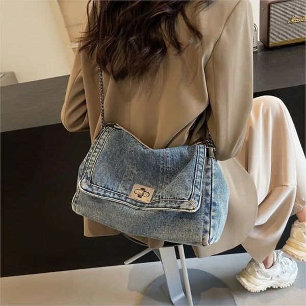 A beige blazer is draped over a person, showcasing a vintage-inspired denim tote bag with a chain strap.