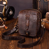 A dark brown genuine cow leather crossbody bag with a crocodile texture resting on a wooden surface.