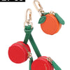Two red cherry fruit shape coin purse keychains with gold hardware and green fabric.